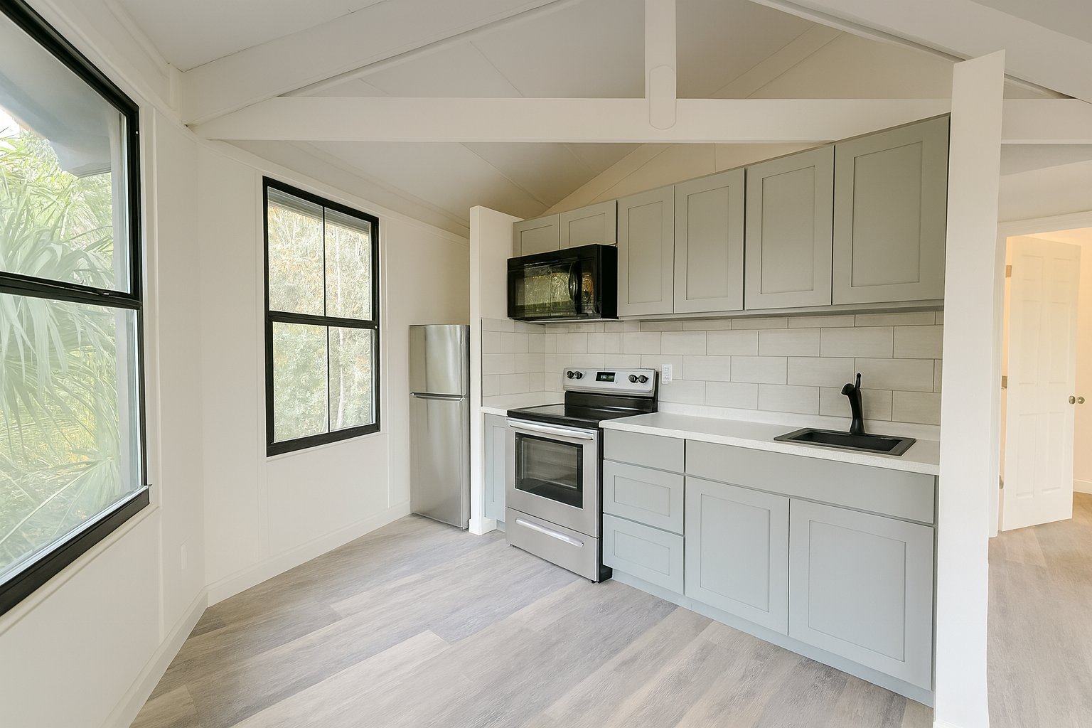 Lake Lofts kitchen with light cabinetry, tiled backsplash and vaulted ceiling